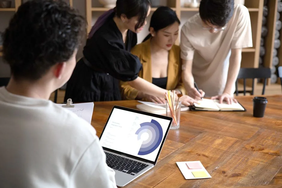 Des mains utilisant un smartphone à côté d'un ordinateur portable avec des graphiques boursiers, illustrant le trading numérique.